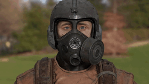 A Man Wearing A Helmet And Gas Mask Looks At The Camera GIF