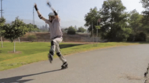 A Man Wearing A Helmet And Knee Pads Is Rollerblading Down A Path GIF