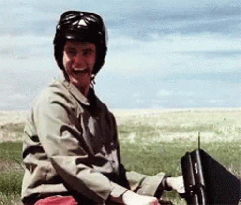A Man Wearing A Helmet Is Sitting In A Field With A Briefcase GIF
