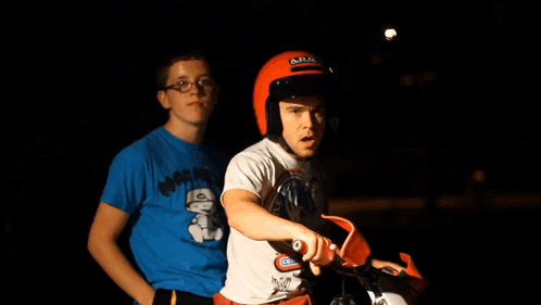 A Man Wearing A Helmet Is Sitting On A Dirt Bike Next To Another Man GIF