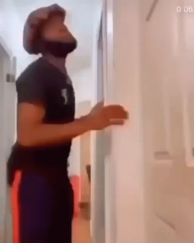 A Man Wearing A Helmet Is Standing In A Hallway . GIF