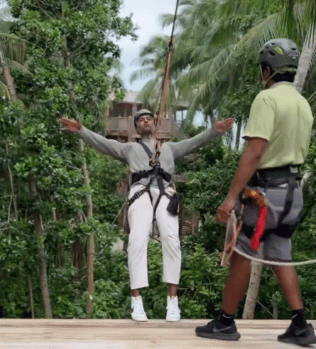 A Man Wearing A Helmet Is Standing Next To A Woman Wearing A Helmet On A Zip Line GIF