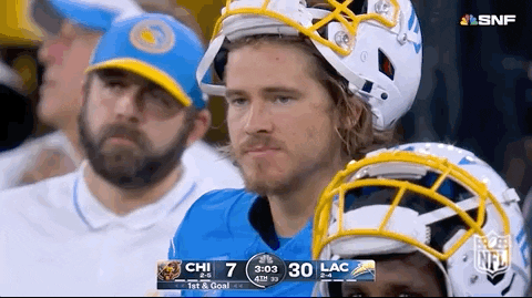 A Man Wearing A Helmet Sits In The Stands Watching A Football Game GIF
