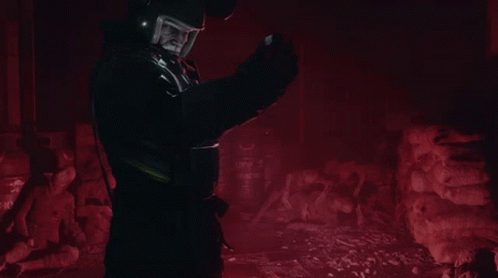 A Man Wearing A Helmet Stands In A Dark Room With Barrels That Say ' Top ' On Them GIF