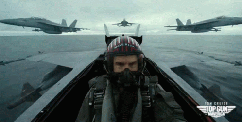 A Man Wearing A Helmet That Says Maverick Is Flying A Plane GIF
