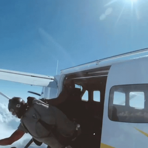 A Man Wearing A Helmet With The Letter B On It Is Getting Out Of A Plane GIF