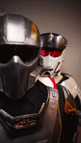 A Man Wearing A Helmet With The Letter T On It Is Standing Next To Another Man GIF