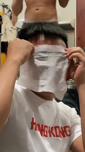 A Man Wearing A Hong Kong T-Shirt Covers His Face With A Piece Of Paper GIF