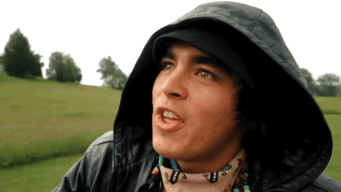 A Man Wearing A Hooded Jacket And A Scarf With A Native American Design On It GIF