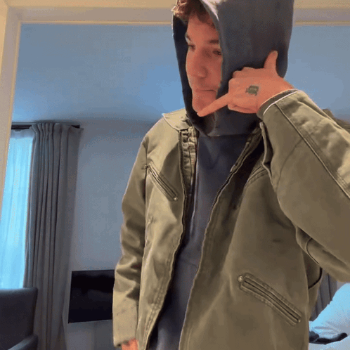a man wearing a hooded jacket has a tattoo on his finger that says ' i love you '