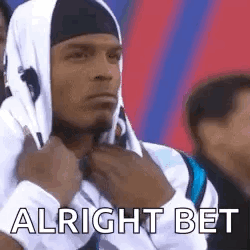 A Man Wearing A Hooded Sweatshirt And A Headband Is Sitting In A Crowd Of People . GIF