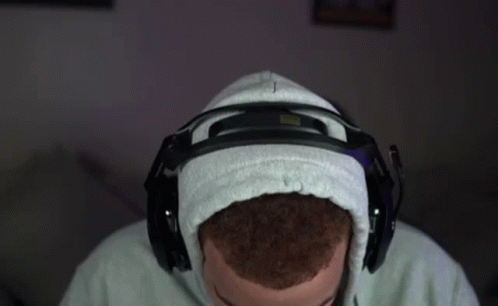 A Man Wearing A Hoodie And Headphones Is Sitting In Front Of A Computer . GIF