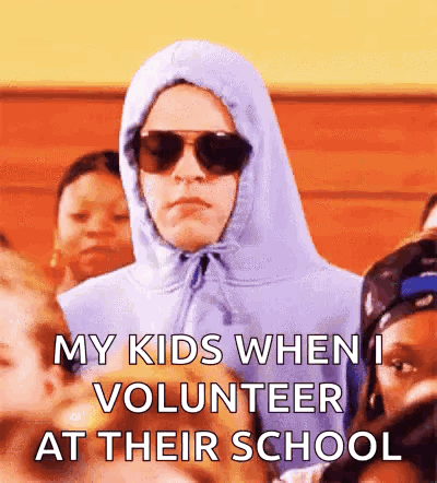A Man Wearing A Hoodie And Sunglasses Is Standing In A Crowd Of Children . GIF