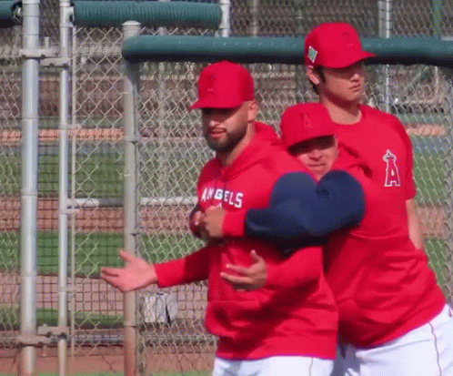 A Man Wearing A Hoodie That Says Angels On It Is Hugging Another Man GIF