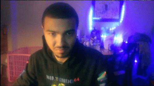 A Man Wearing A Hoodie That Says Nintendo 64 Looks At The Camera GIF