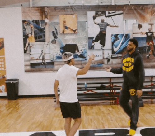 a man wearing a hoodie that says warriors on it talks to another man