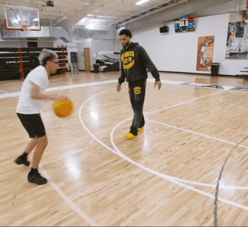 a man wearing a hoodie with the number 23 on it plays basketball