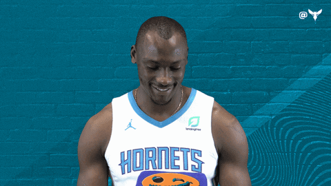 A Man Wearing A Hornets Jersey Smiles In Front Of A Blue Wall GIF