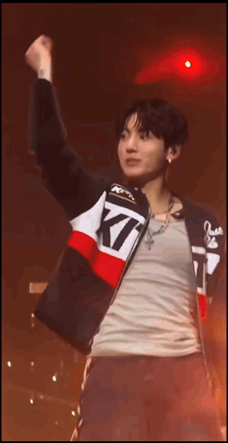 a man wearing a jacket that says kt is raising his fist in the air