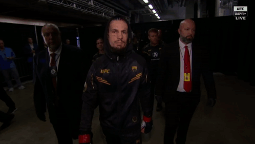 A Man Wearing A Jacket That Says Ufc Is Walking In A Dark Room GIF