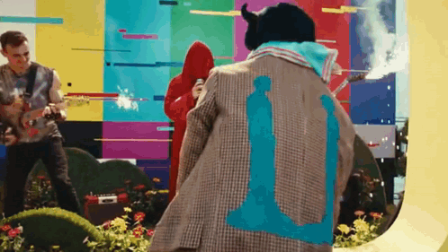 A Man Wearing A Jacket With The Number 11 On It Is Standing In Front Of A Colorful Wall . GIF