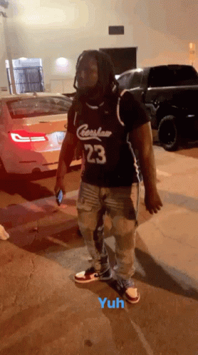 A Man Wearing A Jersey With The Number 23 On It Is Standing In A Parking Lot GIF