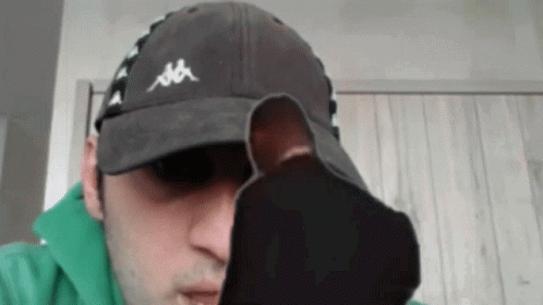 A Man Wearing A Kappa Hat Is Holding A Pair Of Socks In Front Of His Face GIF