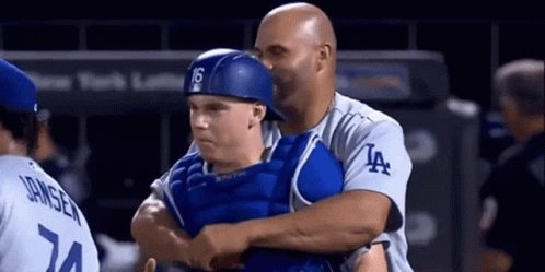A Man Wearing A La Jersey Is Hugging A Baseball Player GIF