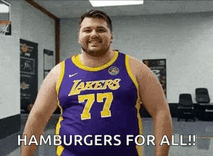 A Man Wearing A Lakers Jersey Is Standing In A Gym . GIF