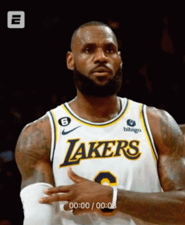 A Man Wearing A Lakers Jersey Is Standing In Front Of A Black Background GIF