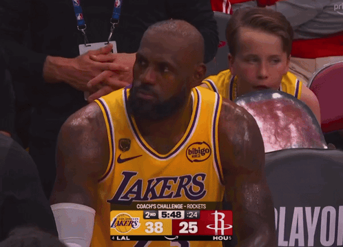 A Man Wearing A Lakers Jersey Sits In A Stadium GIF
