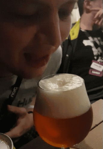 A Man Wearing A Lanyard That Says ' Ncs ' On It Looks At A Glass Of Beer GIF