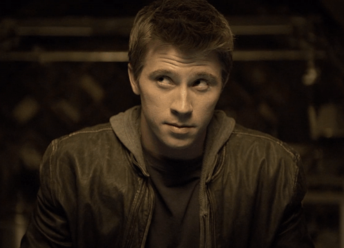 A Man Wearing A Leather Jacket And A Hoodie Looks To His Left GIF
