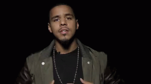 A Man Wearing A Leather Jacket And A Necklace Is Making A Funny Face With His Hands In The Air . GIF