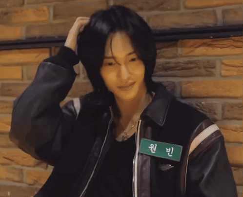 A Man Wearing A Leather Jacket Has A Name Tag That Says Wan Bin On It GIF
