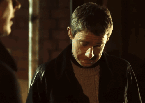 A Man Wearing A Leather Jacket Looks Down At Something GIF