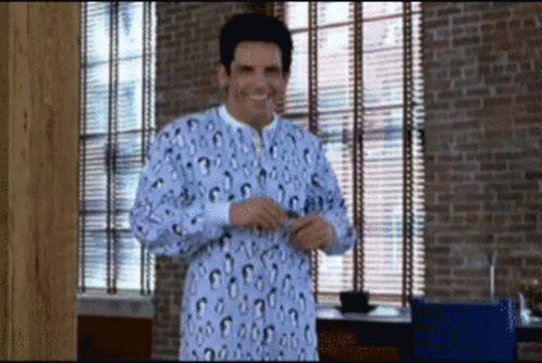 A Man Wearing A Leopard Print Pajama Top Is Standing In Front Of A Window GIF