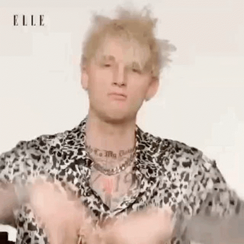 A Man Wearing A Leopard Print Shirt And A Necklace Is Making A Funny Face . GIF