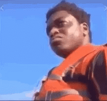 A Man Wearing A Life Jacket Is Looking At The Camera . GIF
