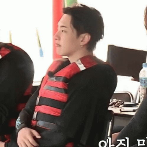 A Man Wearing A Life Jacket Is Sitting On A Chair . GIF