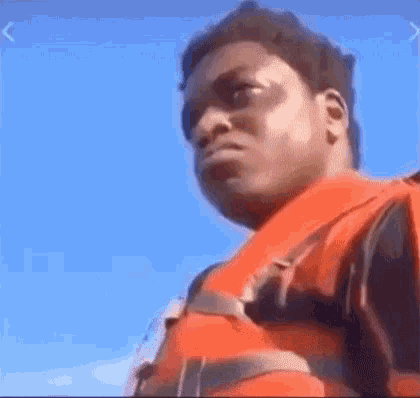 A Man Wearing A Life Jacket Is Standing On A Boat . GIF