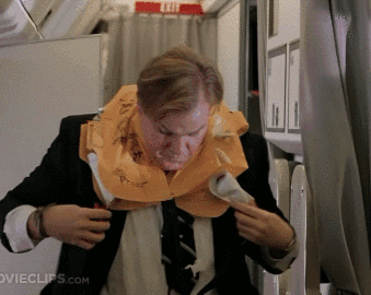 A Man Wearing A Life Vest On An Airplane With Movieclips.com Written Below Him GIF