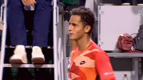 A Man Wearing A Lotto Shirt Stands In Front Of A Referee 'S Chair GIF