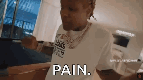 A Man Wearing A Louis Vuitton Shirt Is Standing In A Living Room And Says `` Pain '' . GIF
