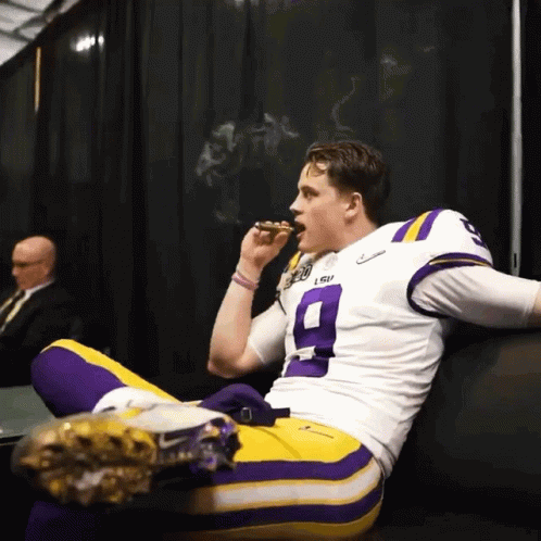 A Man Wearing A Lsu Jersey Is Smoking A Cigar GIF