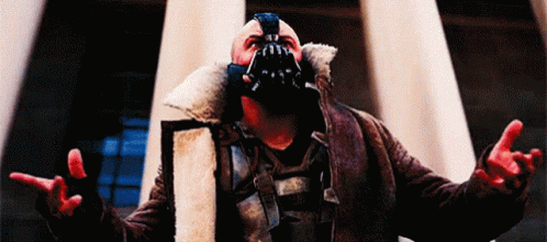 A Man Wearing A Mask And A Fur Coat Is Standing In Front Of A Building . GIF
