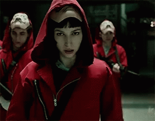 A Man Wearing A Mask And A Hood Is Holding His Hand To His Mouth . GIF