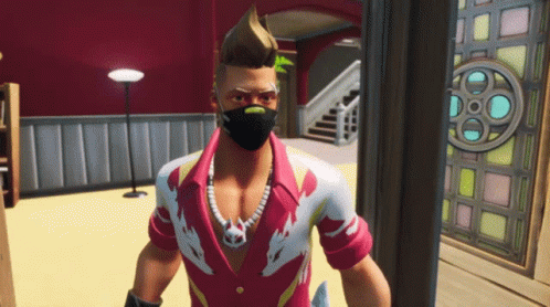 A Man Wearing A Mask And A Necklace Stands In A Room GIF