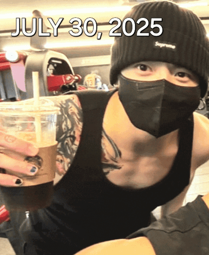 A Man Wearing A Mask And A Supreme Beanie Is Holding A Cup Of Coffee On July 30 2025 GIF