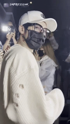 A Man Wearing A Mask And Glasses Is Standing In Front Of A Crowd With The Word Impression Above Him GIF